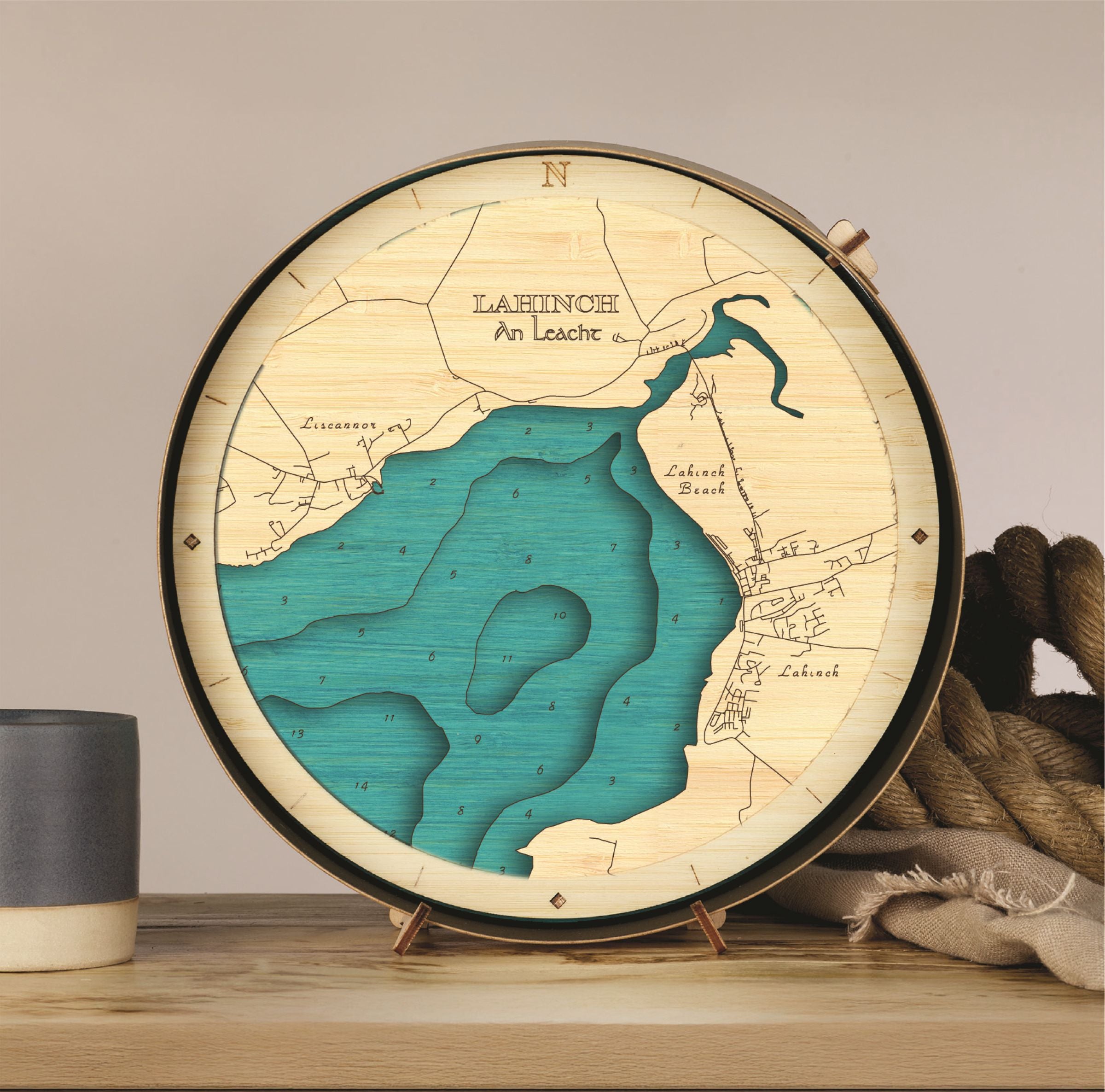 Wooden map of Lahinch on a stand with a cup and blanket in the background