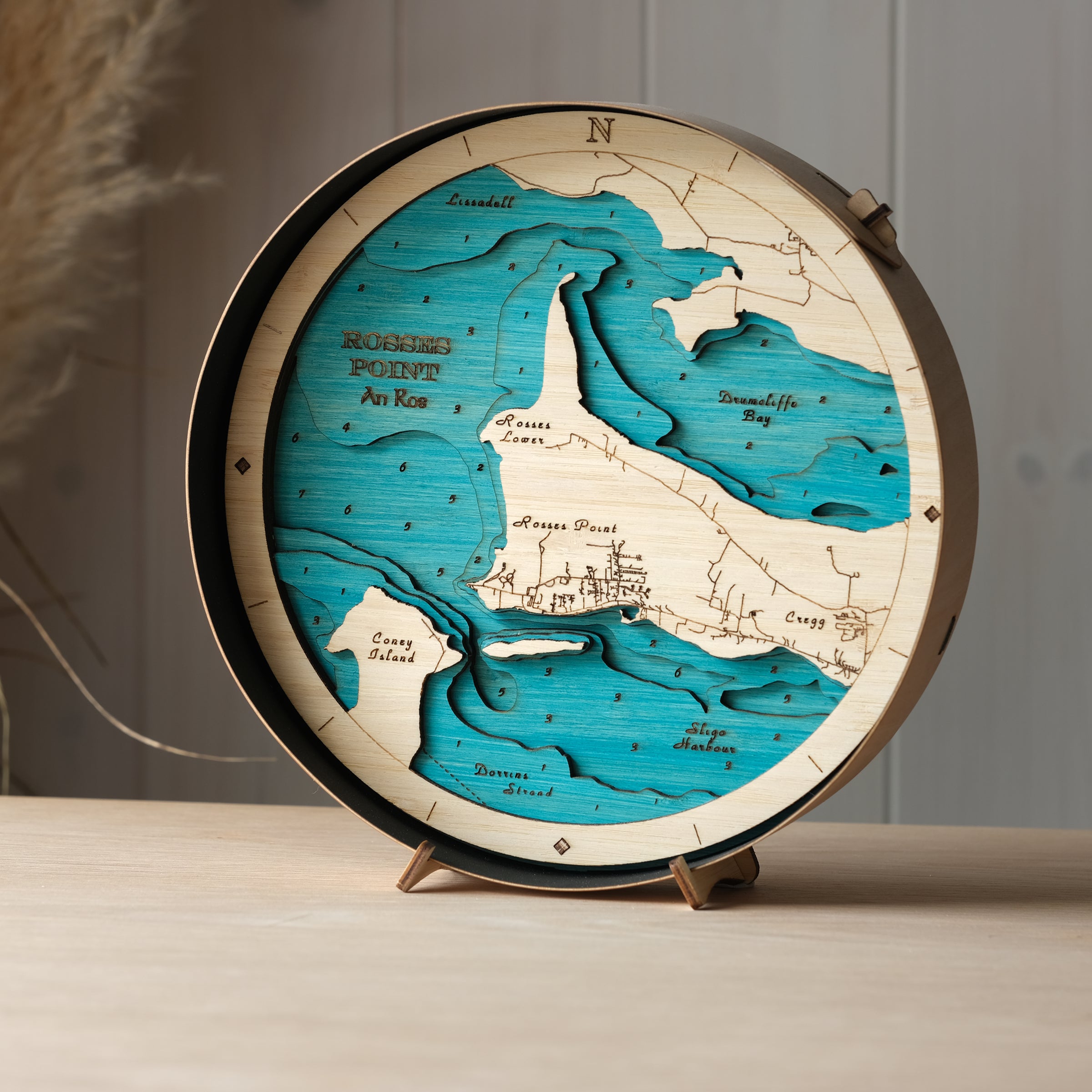 Round 3D wooden map of Rosses Point in black birch frame, displayed on a shelf with stand, handcrafted by Outcrop