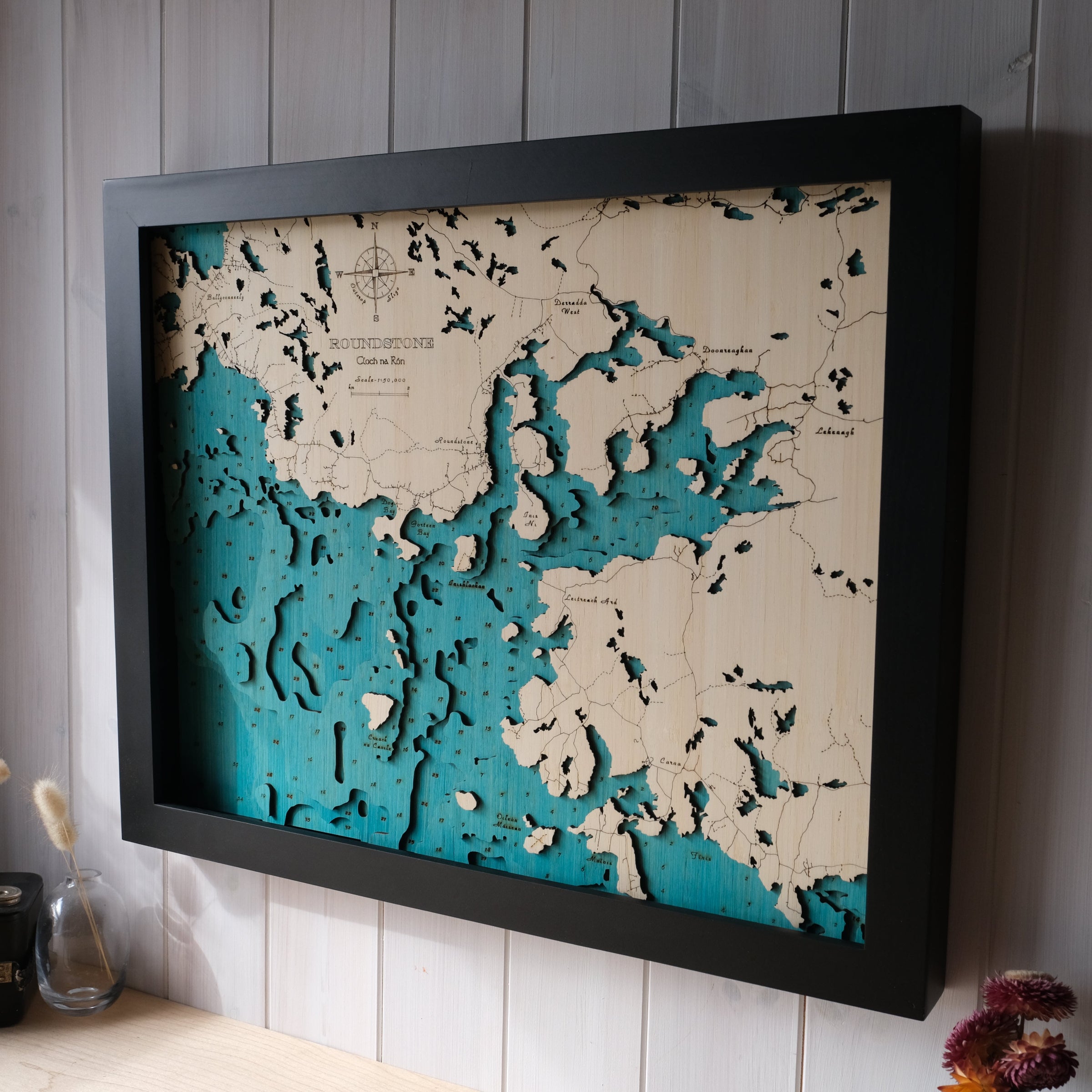 Framed topographic map with blue and beige colors on a wooden surface.