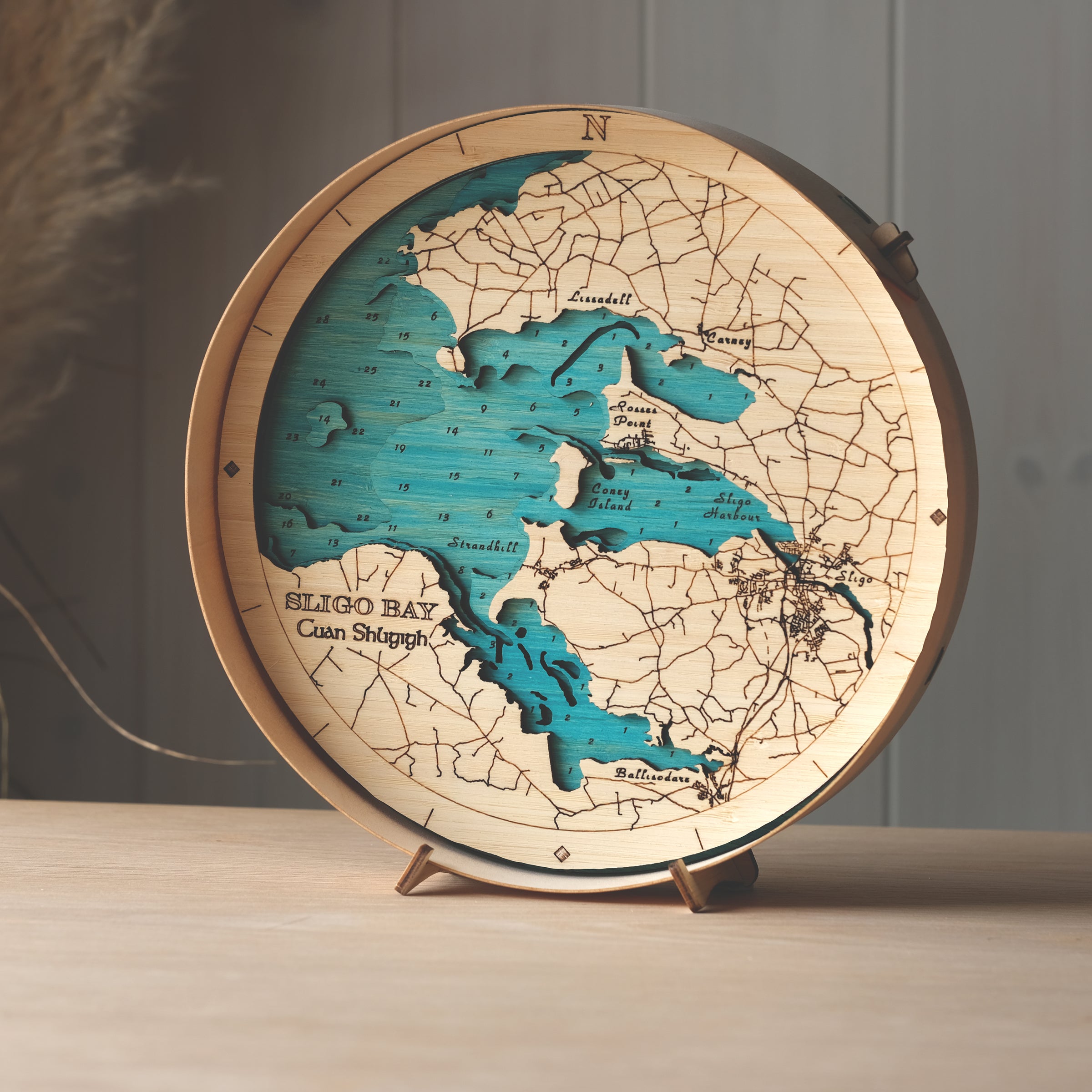 Round 3D wooden map of Sligo Bay in natural birch frame, displayed on a shelf with stand, handcrafted by Outcrop