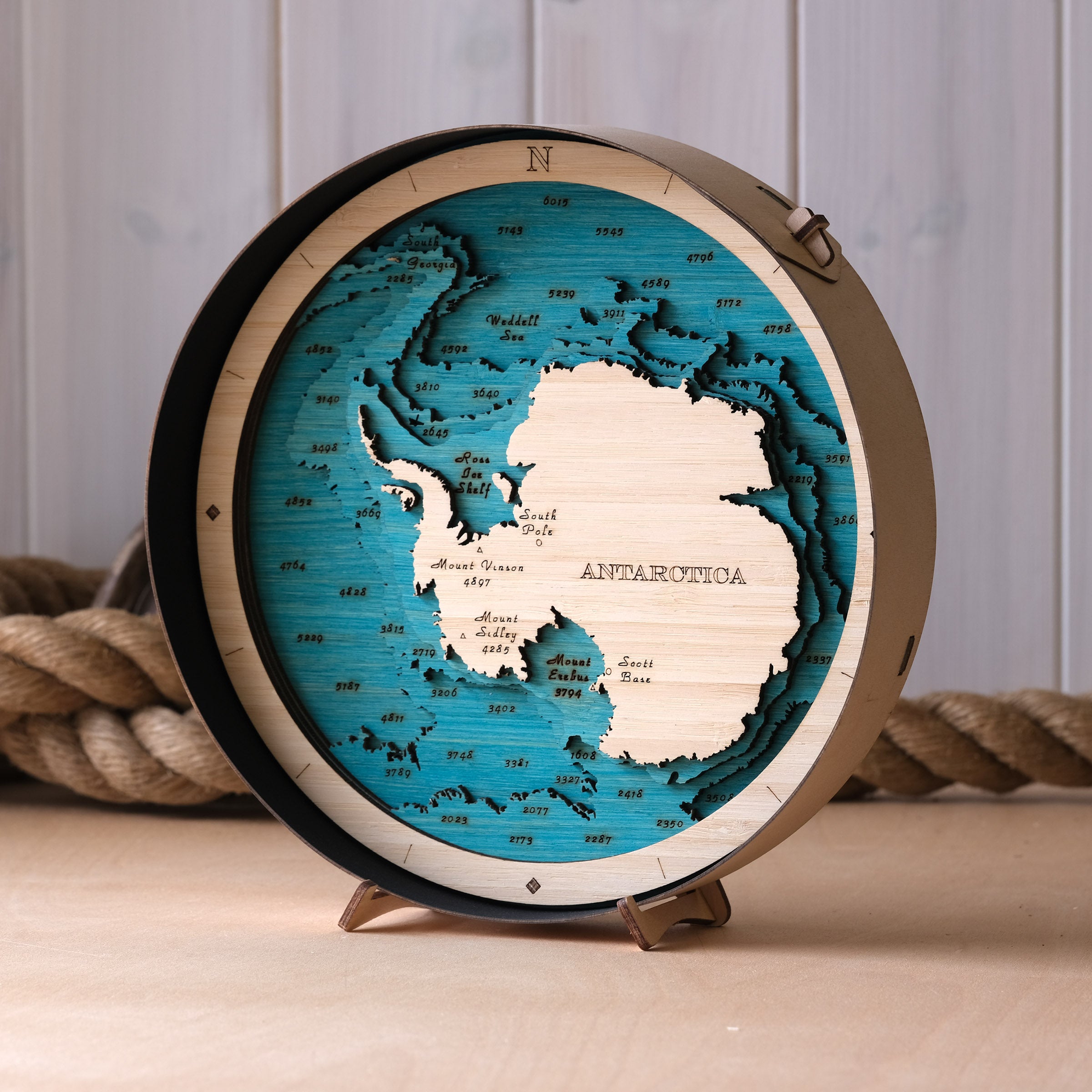 Wooden map of Antarctica on a stand with a rope background