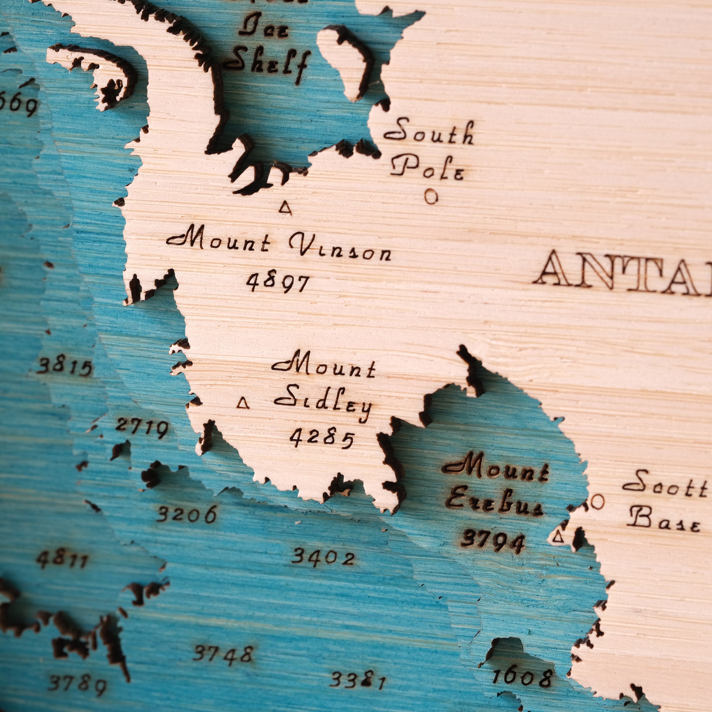 Wooden map of Antarctica with laser-cut details of Scott Base and Mount Erebus and engraved text.