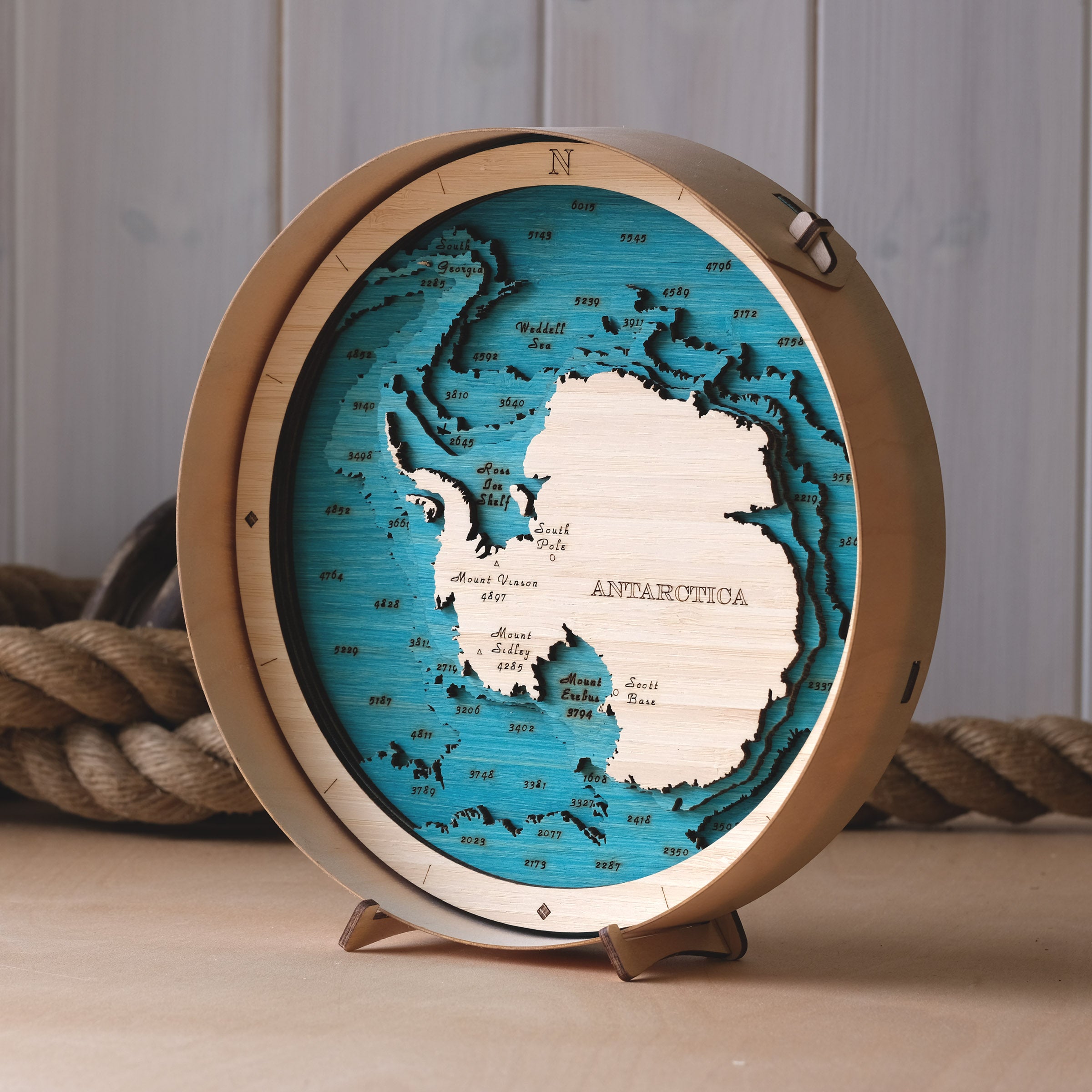 Wooden map of Antarctica with a wooden frame on a wooden surface.