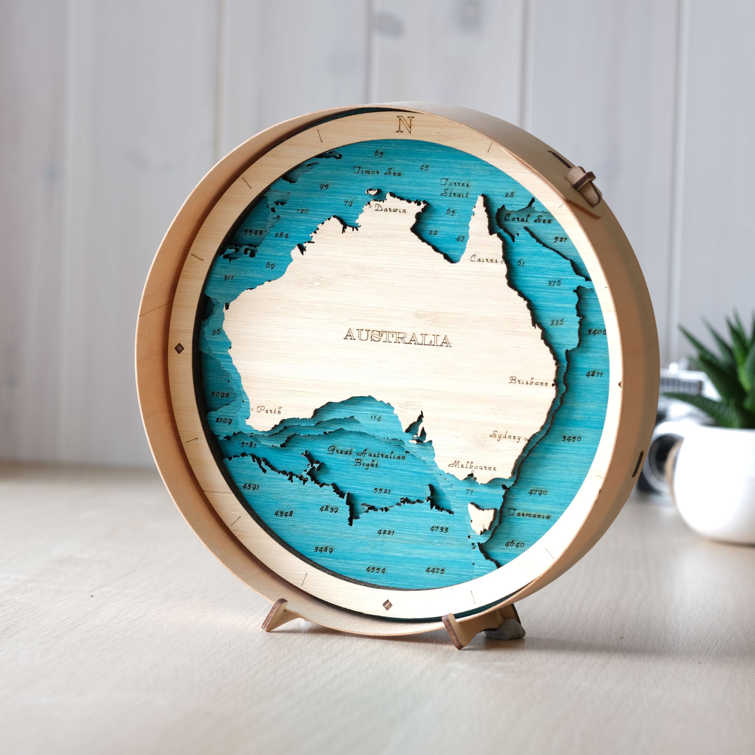 3d round wooden map of Australia on a stand with a natural round wooden frame and a blue stain on the sea color scheme.