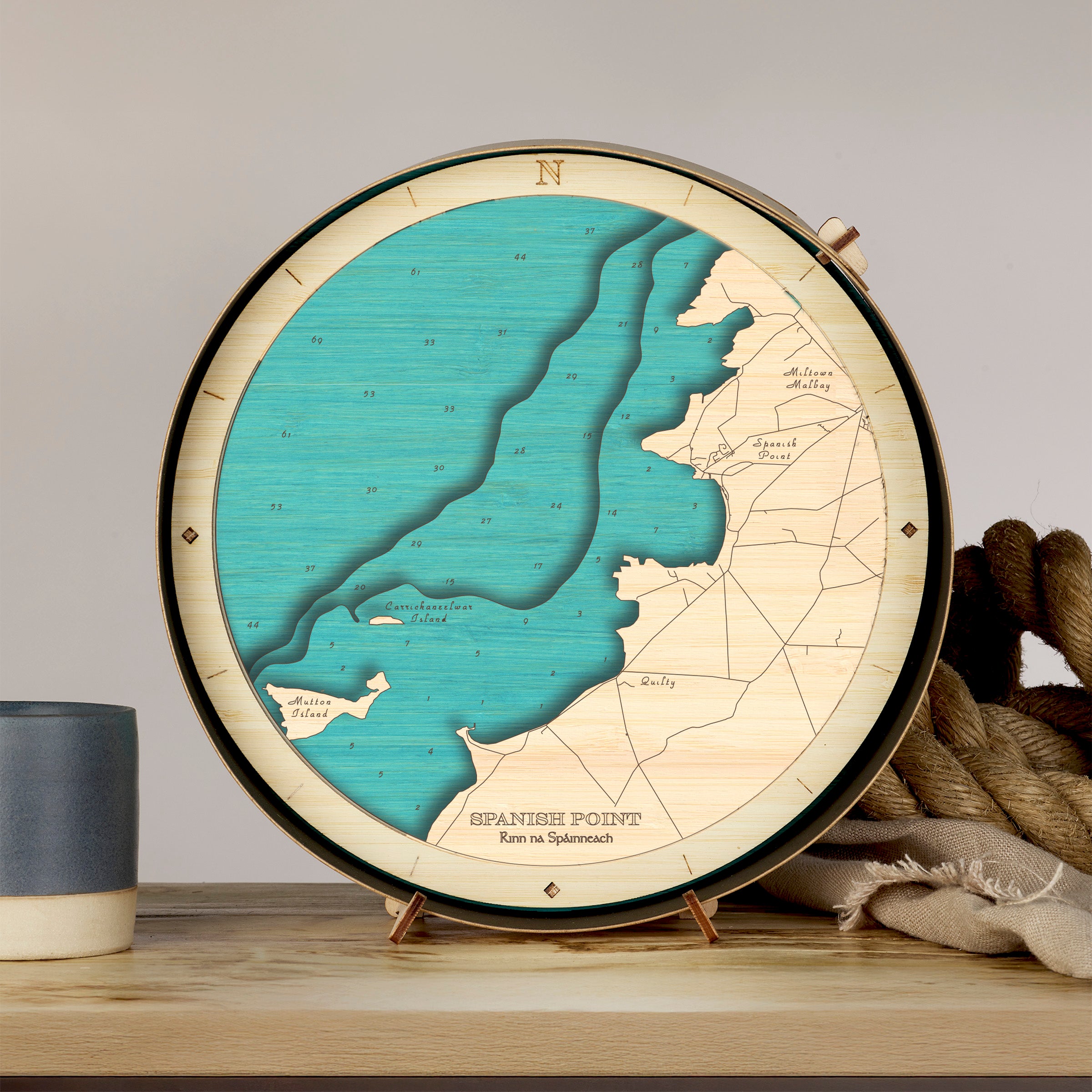 Round nautical wooden chart of Spanish Point on a stand with a cup and rope in the background