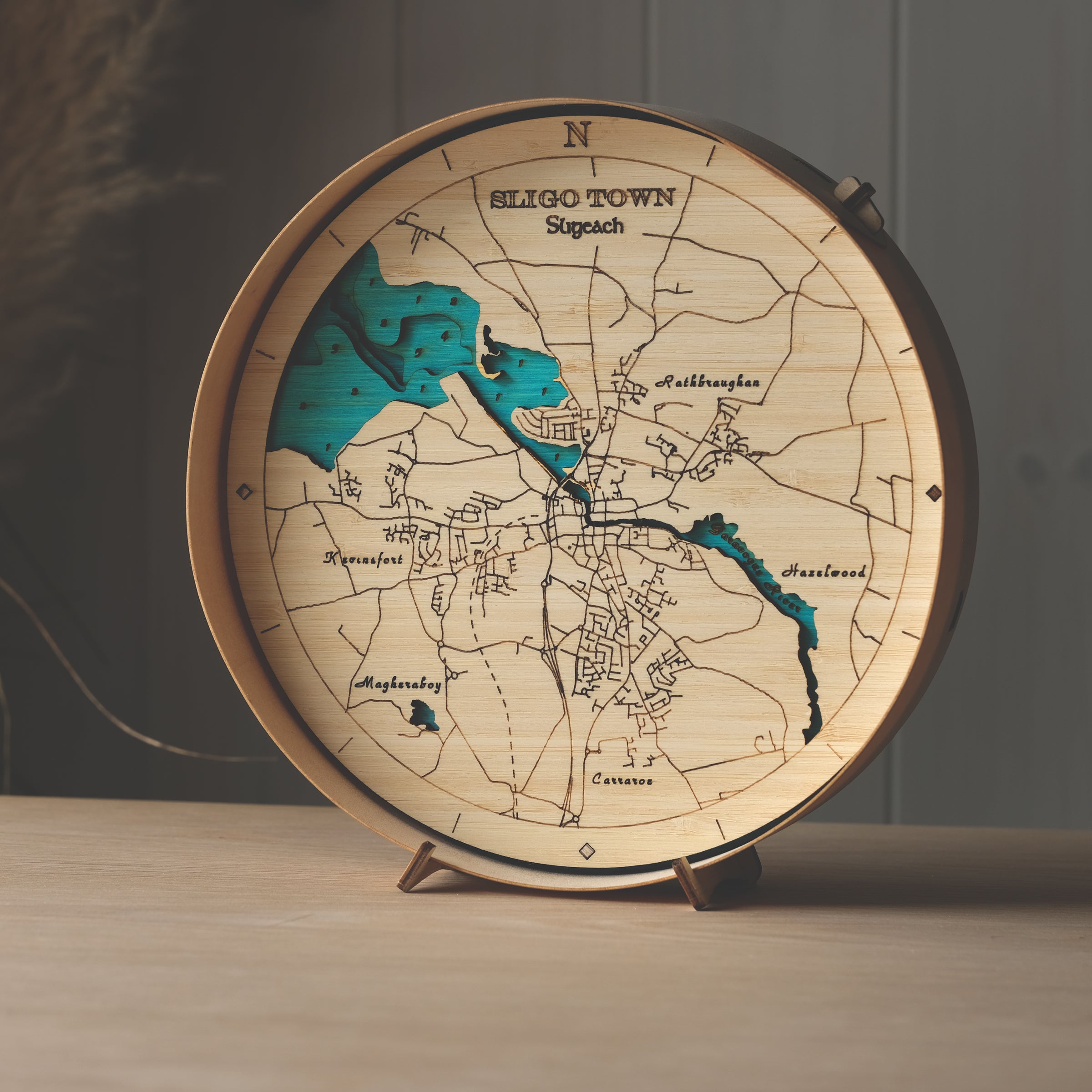 Round 3D wooden map of Sligo town in natural birch frame, displayed on a shelf with stand, handcrafted by Outcrop